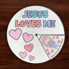 a clock with the words jesus loves me written in pink and blue on it's face