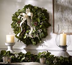 a wreath and two candles on a mantle