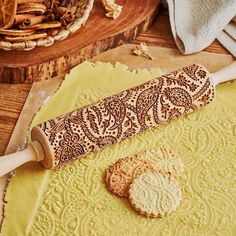 a cookie rolling on top of a table next to a wooden spatula and some cookies