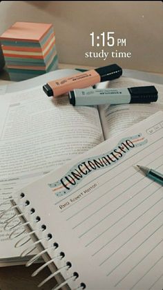 an open book sitting on top of a table next to some pens and pencils