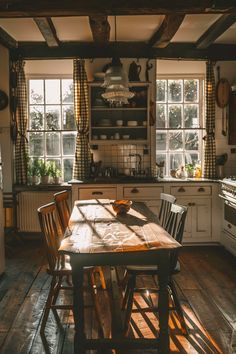 a table and chairs in a room with wooden flooring, windows, and cabinets