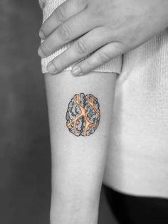 a woman's arm with an orange and black tattoo on the left inner forearm