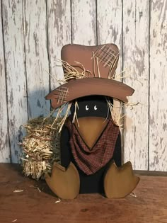 a scarecrow with a hat and scarf sitting in front of a pile of hay