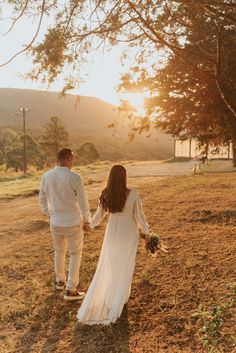 a man and woman holding hands walking in the grass