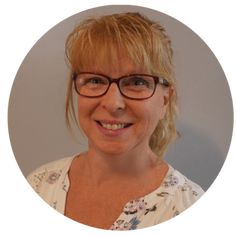 a woman with glasses is smiling at the camera in a circle frame, she has blonde hair and blue eyes