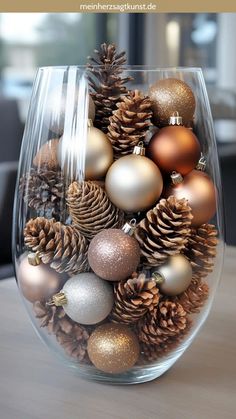 a glass vase filled with christmas ornaments on top of a table