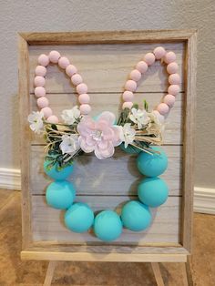 a wooden frame with beads and flowers on the front is decorated in pastel colors