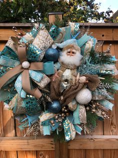 a christmas wreath with a santa clause and ornaments hanging on a wooden fence in front of a house