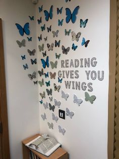 a wall with butterflies and the words reading gives you wings written on it next to a book