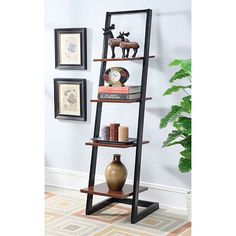 a leaning shelf with books on it in front of a white wall and potted plant