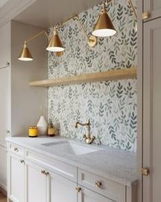 a kitchen with two sinks and three lights hanging from the ceiling above it, along with white cabinets