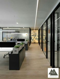 an empty office with desks and planters in the center, along with glass walls