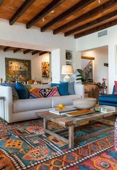 a living room filled with lots of furniture and colorful pillows on top of it's couches