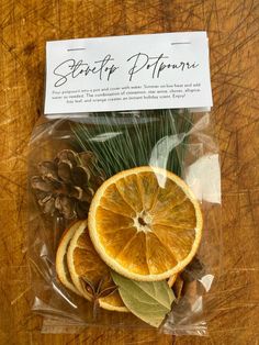 an orange cut in half sitting on top of a piece of waxed paper next to pine cones