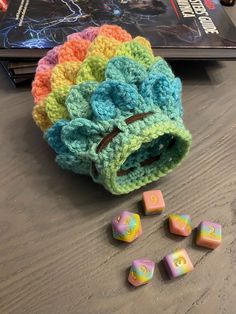 a crocheted bag with dices on the floor next to it and a book