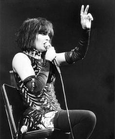 a woman sitting on top of a chair while holding a microphone in her right hand