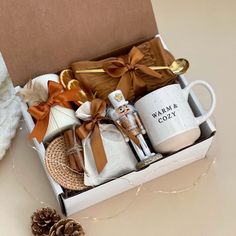 a gift box with coffee, mugs and other items in it next to a pine cone