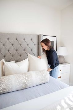 a woman holding pillows on top of a bed