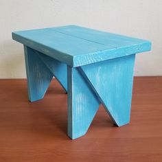 a blue wooden stool sitting on top of a wooden floor