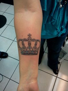 a person with a tattoo on their arm that has a crown and cross on it