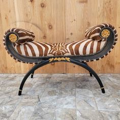 a zebra print bench sitting on top of a tile floor next to a wooden wall