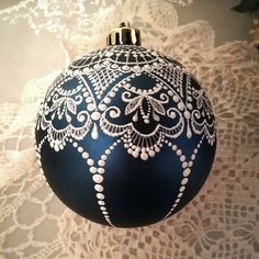 a blue ornament sitting on top of a white lace covered table cloth next to a wall