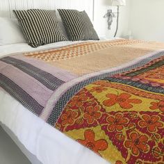 a bed with colorful blankets and pillows on top of it