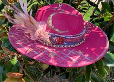 "The Dolly" This wool like cream/white WIDE BRIM  hat has been hand dyed & hand painted with bright pink, gold & white. Hat band is blue Jean , chiffon, beads & gold chain. Several rhinestone butterflies, rhinestones, gold leaf, dried flowers & feathers. "What would Dolly do" pin.  Show your love for Dolly Parton & 9-5 style with this one of a kind walking art piece.  Polyester material Size 59cm   Brim: 4" Hat Height 5"  Please read hat measurements before purchasing  **Hats do not run small or large, they are just as the measurements are listed** **Do not wash, dry or iron...wipe with lightly dampened clothe" Bohemian Pink Hat Band For Kentucky Derby, Handmade Pink Fedora For Spring, Hand Painted Hats With Curved Brim For Country Events, Whimsical Handmade Fedora For Kentucky Derby, Handmade Whimsical Fedora For Kentucky Derby, Pink Short Brim Felt Hat For Festival, Pink Bohemian Hats For Country Events, Pink Bohemian Hat For Country Events, Pink Hat For Kentucky Derby Festival