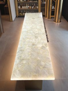 a white marble counter top in a room with shelves and lights on the wall behind it