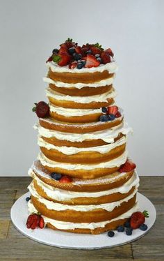 a multi layer cake with strawberries and blueberries on top