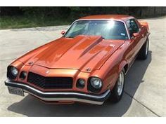 an orange muscle car parked in a parking lot