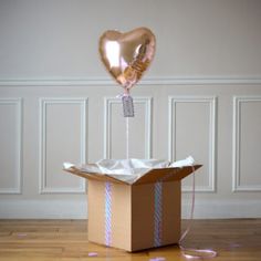 a box with a heart shaped balloon in it