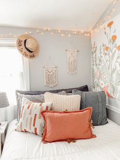 a white bed topped with lots of pillows next to a wall covered in string lights