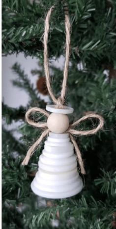 a white bell ornament hanging from a christmas tree