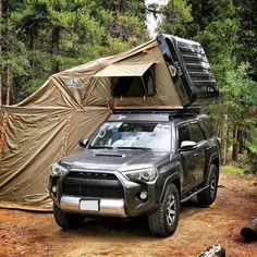 an suv parked in the woods with a tent on top