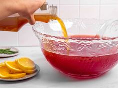 someone pouring orange juice into a glass bowl