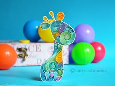 a paper giraffe standing in front of colorful balloons