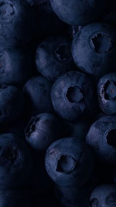 blueberries with holes in the middle are piled on top of each other and dark background