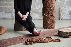 a woman is sitting on the floor with her feet propped up in front of a piece of wood