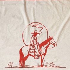 a red and white towel with a cowboy riding a horse in the desert under a full moon