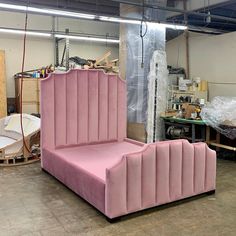 a large pink bed sitting inside of a room next to other furniture and tools on the floor