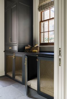 a kitchen with black cabinetry and gold hardware on the doors, along with a dog bed