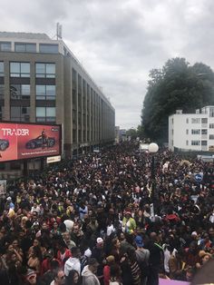 a large group of people standing in front of a tall building on a city street