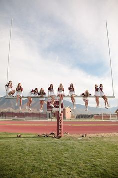 a group of girls are hanging upside down on a pole in the middle of a track