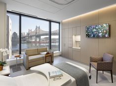 a bedroom with large windows and a view of the bridge over the water in new york city