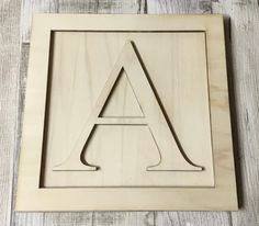 an unfinished wooden sign with the letter a in it's center on a white wood background