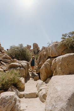 a woman is walking up some rocks in the desert