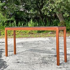 a wooden table sitting on top of a gravel field