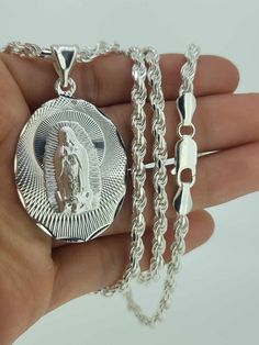 Classic 925 Silver Virgin Mary pendant and necklace set! This set includes solid rope chain and Virgin Mary diamond cut pendant in 925 silver. Necklace measures 26 inches long by 4mm wide, pendant measures 1 1/2 in. tall by 27mm wide.  Set clásico de La Virgencita en plata 925. Este set incluye cadena solida torsal y colgate de la Virgencita con corte diamantado. La cadena mide 26 pulgadas de largo por 4mm de ancho, colgante mide 1 1/2 pulgadas de alto por 27mm de ancho. .925 Sterling Silver Catholic Jewelry, Silver Rope Chain With Round Pendant, Silver Pendant With Rope Chain, Silver Pendant Rope Chain Jewelry, Silver Rope Chain Pendant, Silver Pendant Necklace With Rope Chain, Sterling Silver Jewelry With Rope Chain, Sterling Silver Rope Chain Necklace Gift, Virgin Mary Pendant