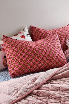 a bed with pink and brown pillows on it's headboard, next to a teddy bear